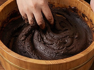 Dark aromatic paste worked by hand in a wooden basin