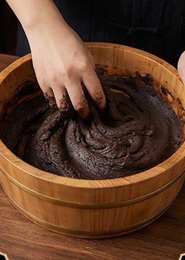 Dark aromatic paste worked by hand in a wooden basin