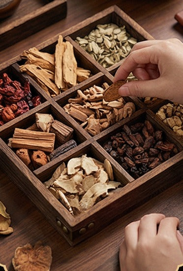Whole botanicals laid out in a compartmented wooden tray, picked over by hand