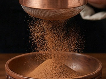 Powder sifted through a copper sieve into a carved wooden bowl