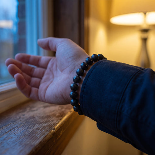 Ink & Angelica hand-rolled incense bead bracelet worn on a wrist at a windowsill at dusk